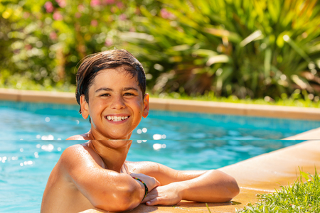 Smiling boy relaxing at outdoor swimming poolの写真素材