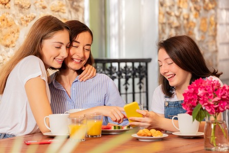 Girl showing her mom something on smart phoneの写真素材