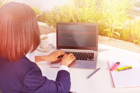 Woman working with laptop computer at street cafe
