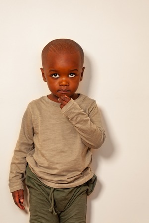 Portrait of calm black boy with hand near chin
