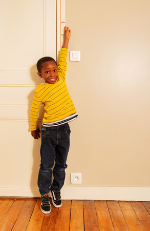 boy stretch his hand to measure height on doorの写真素材