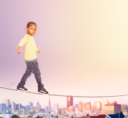 Handsome black boy walking on the rope over cityの写真素材