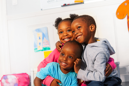 Three happy little black kids close portrait hugの写真素材