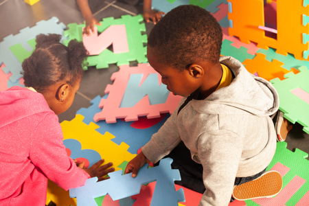 Two kids black boy and girl play with lettersの写真素材