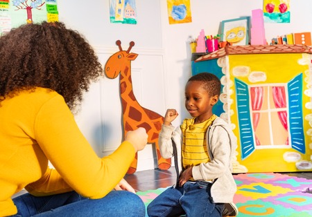 Teacher and little boy play rock paper scissorsの写真素材
