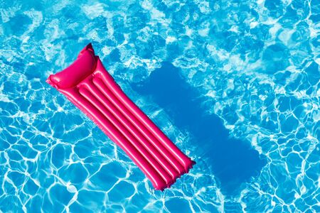 Pink inflatable mattress floating on water surfaceの写真素材