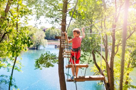 Little boy walk on the rope bridge between treesの写真素材