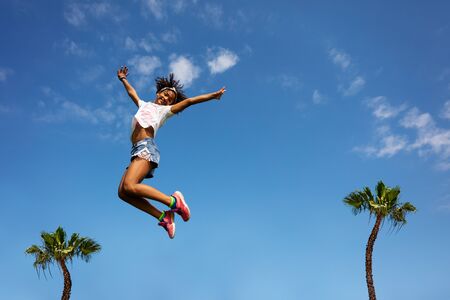 Cute girl in jump over sky with palms lift hands