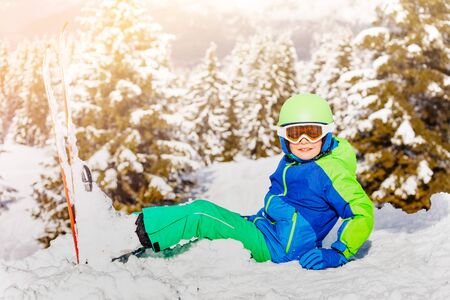 Boy in snow with ski sit over white forest treesの写真素材