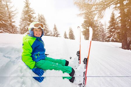 Happy boy rest siting on the slope side with skiの写真素材