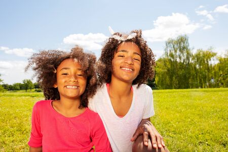 Two happy smiling girls in park lawn portraitの写真素材