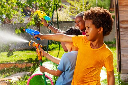 Boy with group of children shoot water pistolの写真素材