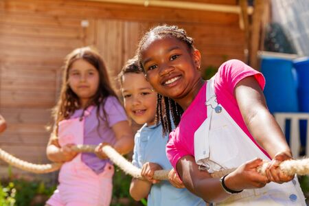 Smiling girl pull rope with friends in competition
