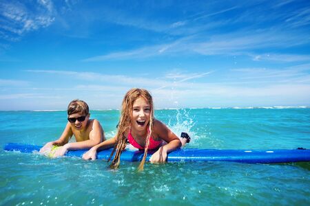 Brother and sister swim for fun on surf boardの写真素材