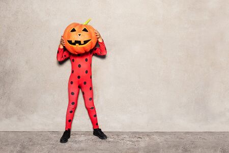 Girl in ladybug costume with head of big pumpkinの写真素材
