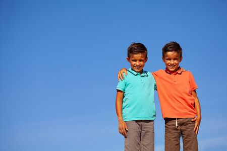 Close portrait of two boys hug over blue skyの写真素材