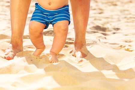 Close-up of baby and mother legs on the sand beach