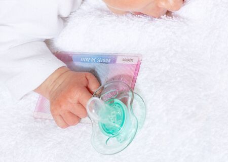French European resident permit Titre de sejour in hand of little baby infant boy and pacifier