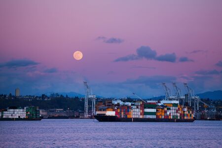 Cargo ship with containers in Seattle port at night over lune in the sky, Washington, USAの写真素材
