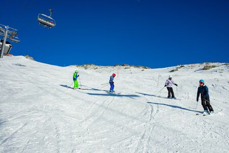Four kids ski downhill in Alpine slope in school formation together one after anotherの写真素材