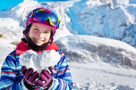 Happy young girl in winter outfit and ski googles, mask hold snow in star shape depicting love mountain vacation concept, close portraitの写真素材