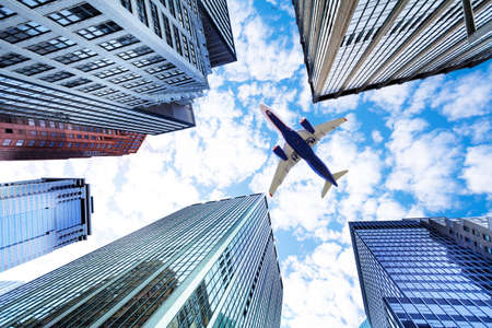 Airplane over sky between skyscraper buildings in New Yorkの写真素材