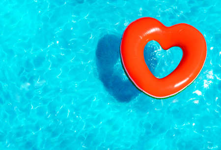 Inflatable red heart buoy swim in the swimming pool view from aboveの写真素材