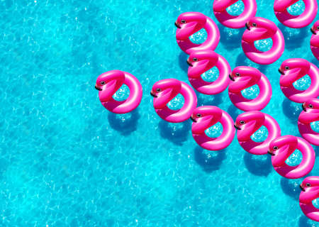 Large group of inflatable flamingo buoy swim in the swimming pool view from aboveの写真素材