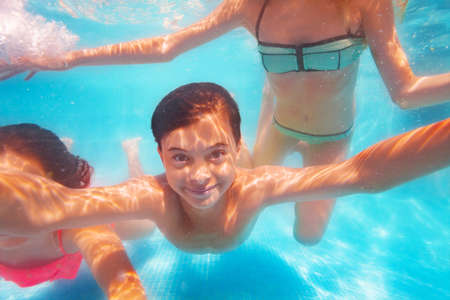 Portrait of a boy in a group of friends dive in the pool and make selfie