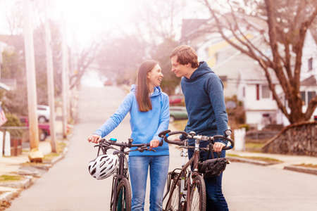 Young couple walk and closely talk holding bikes on the street in USAの写真素材