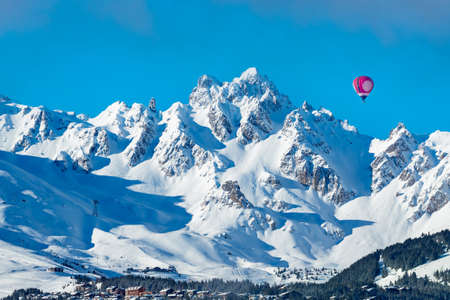 Vivid red colorful hot air balloon over Courchevel valley in French Alpsの写真素材