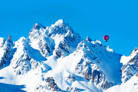 Colorful hot air balloon over high French Alps mountain peaks on sunny dayの写真素材
