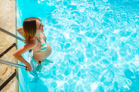 View a pregnant woman enters the swimming pool portrait from aboveの写真素材