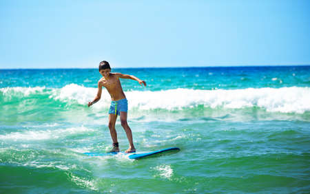 Happy boy ride surfboard on waves confidently surfing photo over seaの写真素材