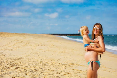 Mother and little toddler on the sea sand beachの写真素材
