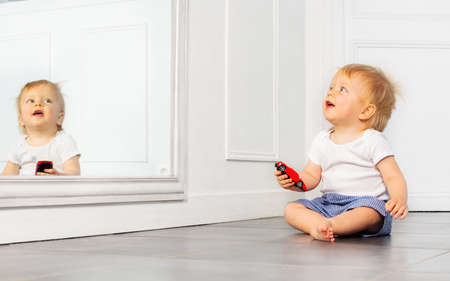 Happy toddler boy play with toy car near mirrorの写真素材