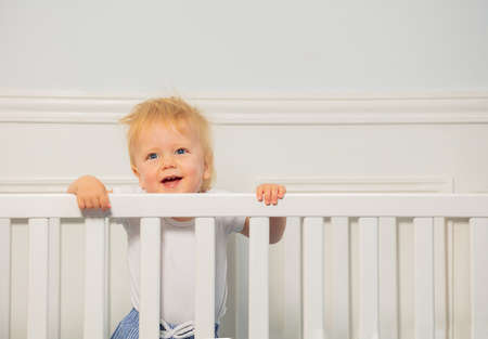 Portrait of a dancing toddler boy in the baby cribの写真素材