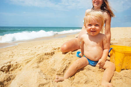 laughing toddler boy sit on the beach and smileの写真素材