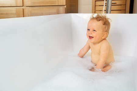 Little toddler blond boy play in a bath with foamの写真素材