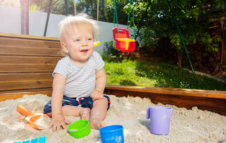 Handsome blond boy play in sandbox smilingの写真素材