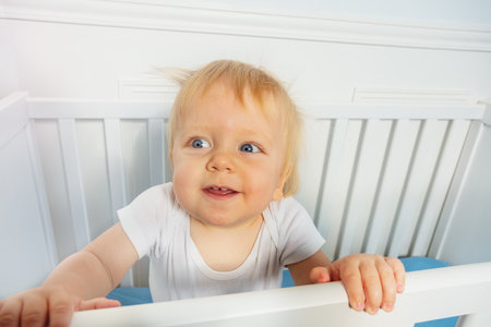Curious portrait of toddler boy in the cribの写真素材