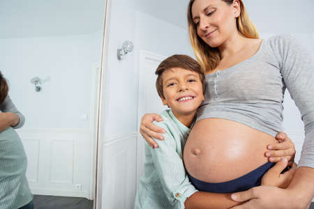 Pregnant mother with big belly hug smile togetherの写真素材