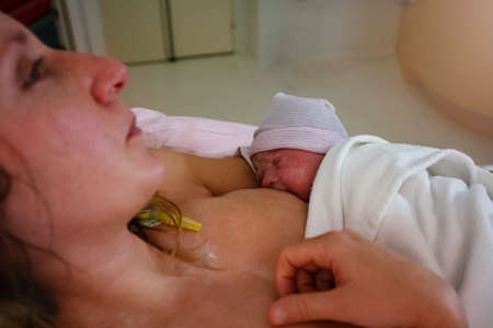 Newborn baby in mothers hands after giving birthの写真素材