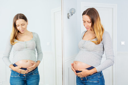 Pregnant 9 month woman and reflection in a mirrorの写真素材