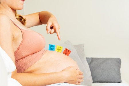Pregnant woman point hand to boy letter on bellyの写真素材