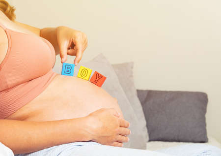Pregnant woman hold with hand boy letters on bellyの写真素材