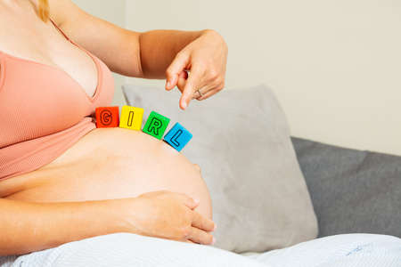 Girl word made of toy blocks on big pregnant bellyの写真素材