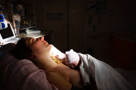 Newborn baby in womans hands after giving birthの写真素材