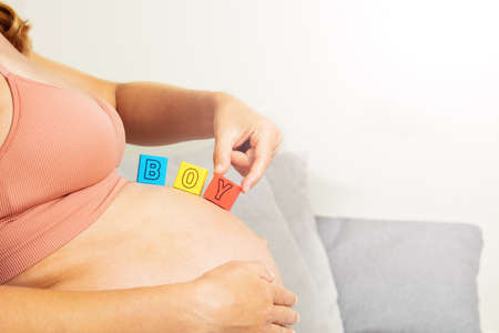 Pregnant woman touch hand to boy letter on bellyの写真素材