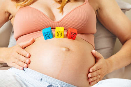 Pregnant woman and boy word letter blocks on bellyの写真素材